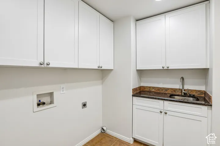 White shaker cabinetry with silver-tone hardware, dark countertop with undermount sink, mosaic tile backsplash, and tile flooring