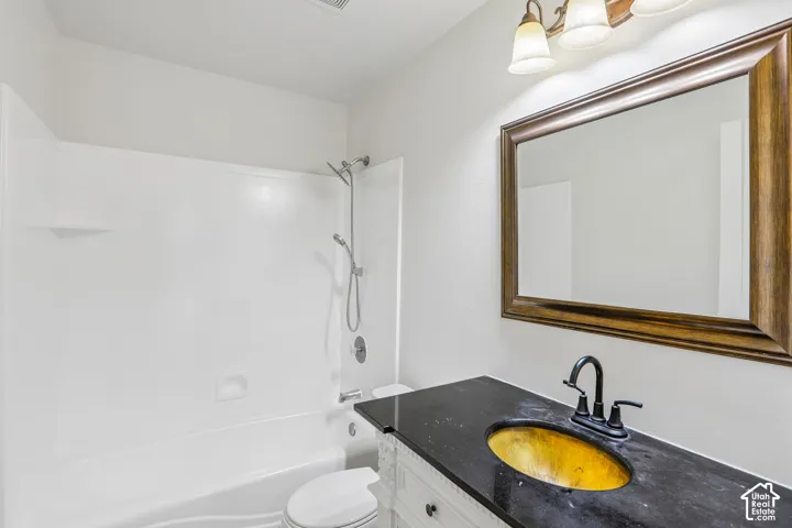 Bathroom featuring a built-in shower/tub combination, vanity with a dark countertop, and a framed wall mirror
