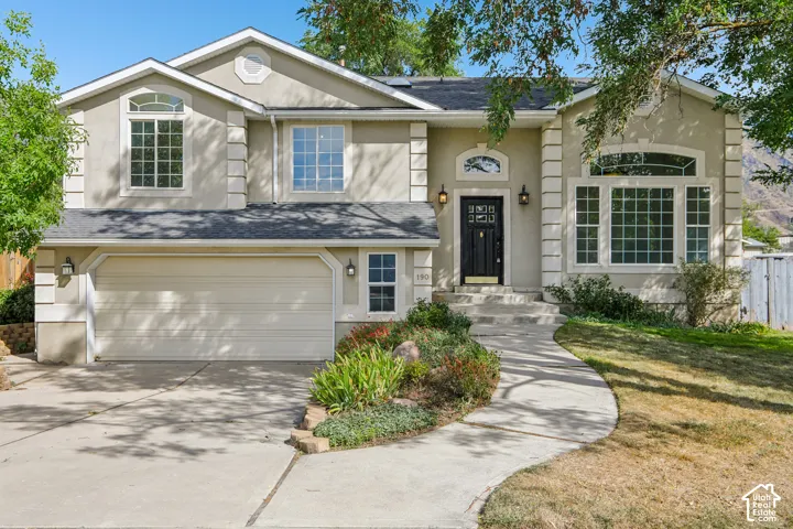 Stucco exterior with decorative trim, arched entry over a paneled front door, attached two-car garage, and a curved concrete walkway