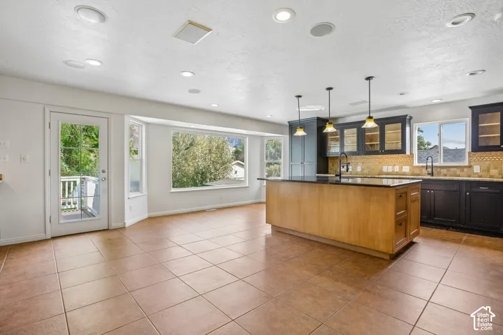 Kitchen with wood-finish island, dark cabinetry, and pendant lighting