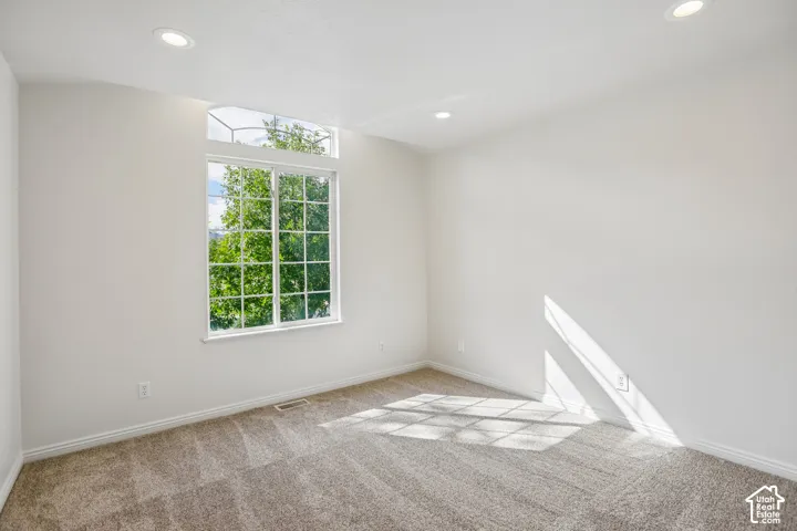 Recessed ceiling lighting, white walls, large window with transom, and neutral carpet flooring