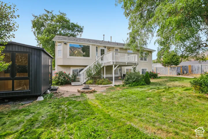 Exterior featuring an upper-level deck with white railings, a lower-level patio, and a fire pit