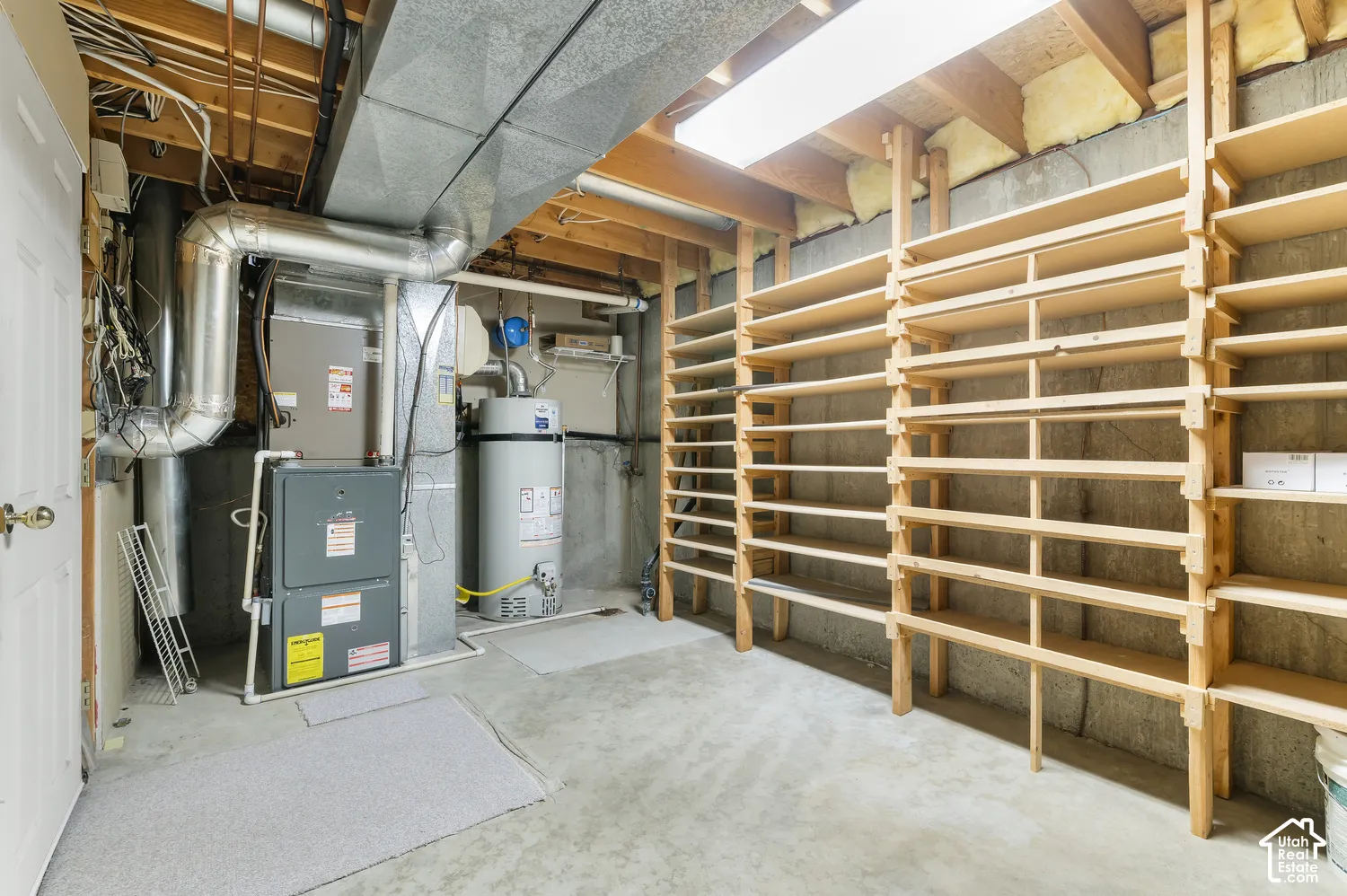 Utility room featuring a water heater, furnace, and extensive built-in wooden shelving for ample storage