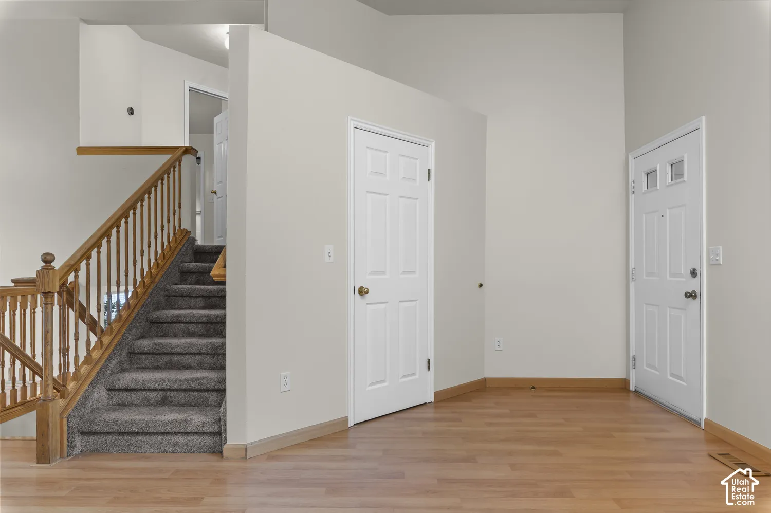 Wood-finish flooring, staircase with wood railing and carpeted treads, white paneled doors, and painted walls