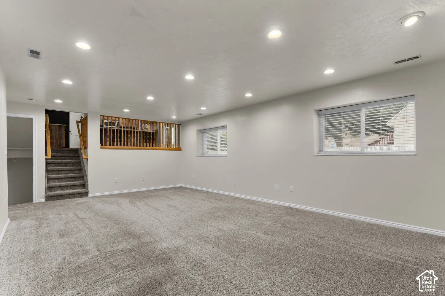 Spacious living area featuring neutral carpeting, recessed lighting, and multiple windows