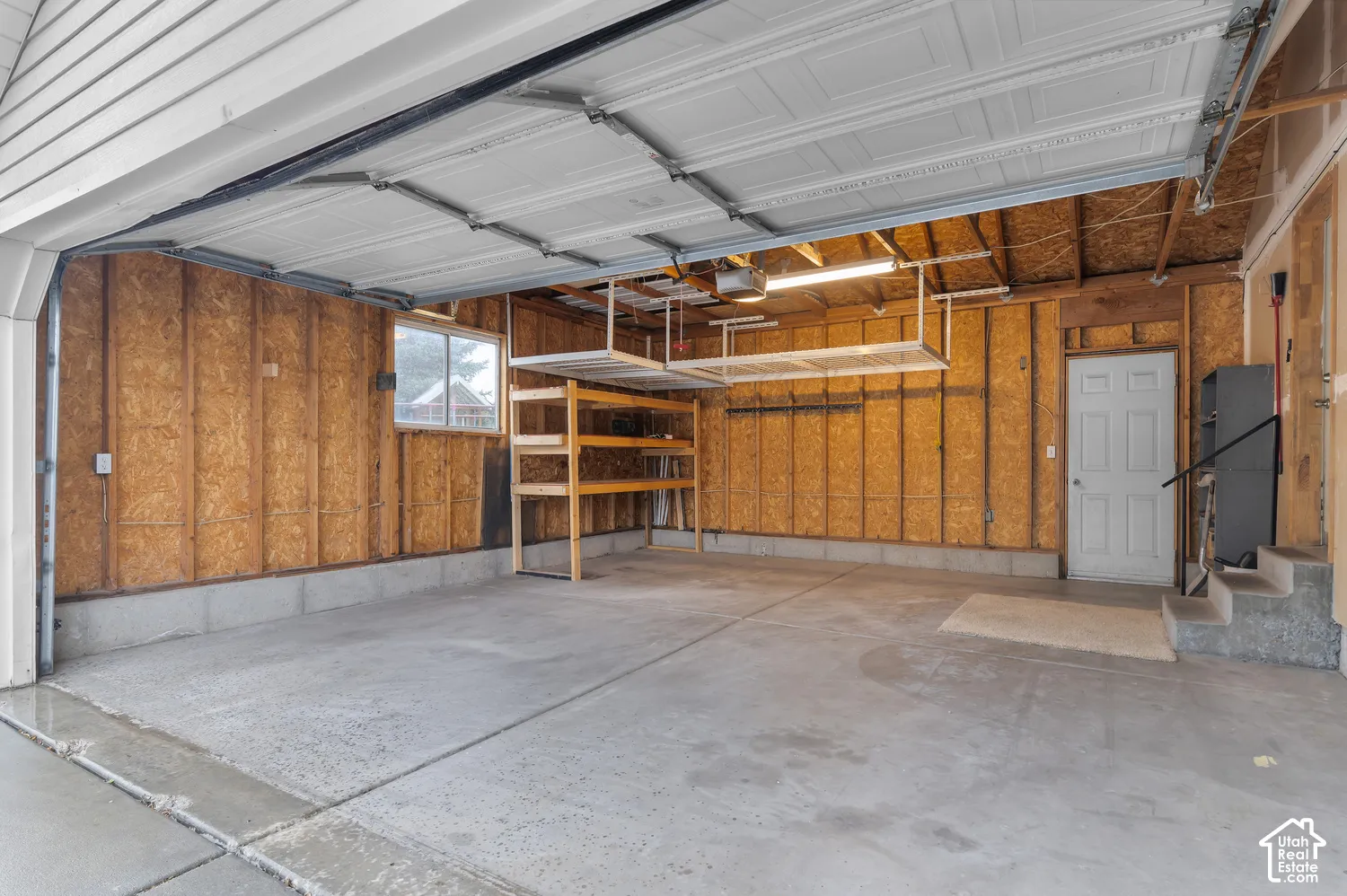 Concrete flooring with overhead storage racks, built-in shelving, and a window
