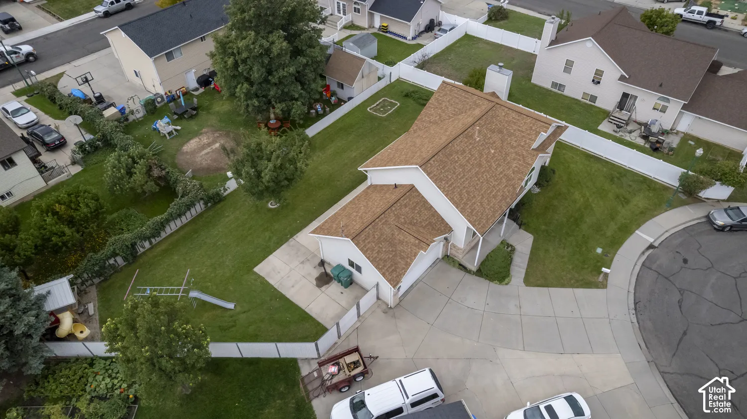 Residential property featuring a spacious backyard, mature trees, and a concrete driveway