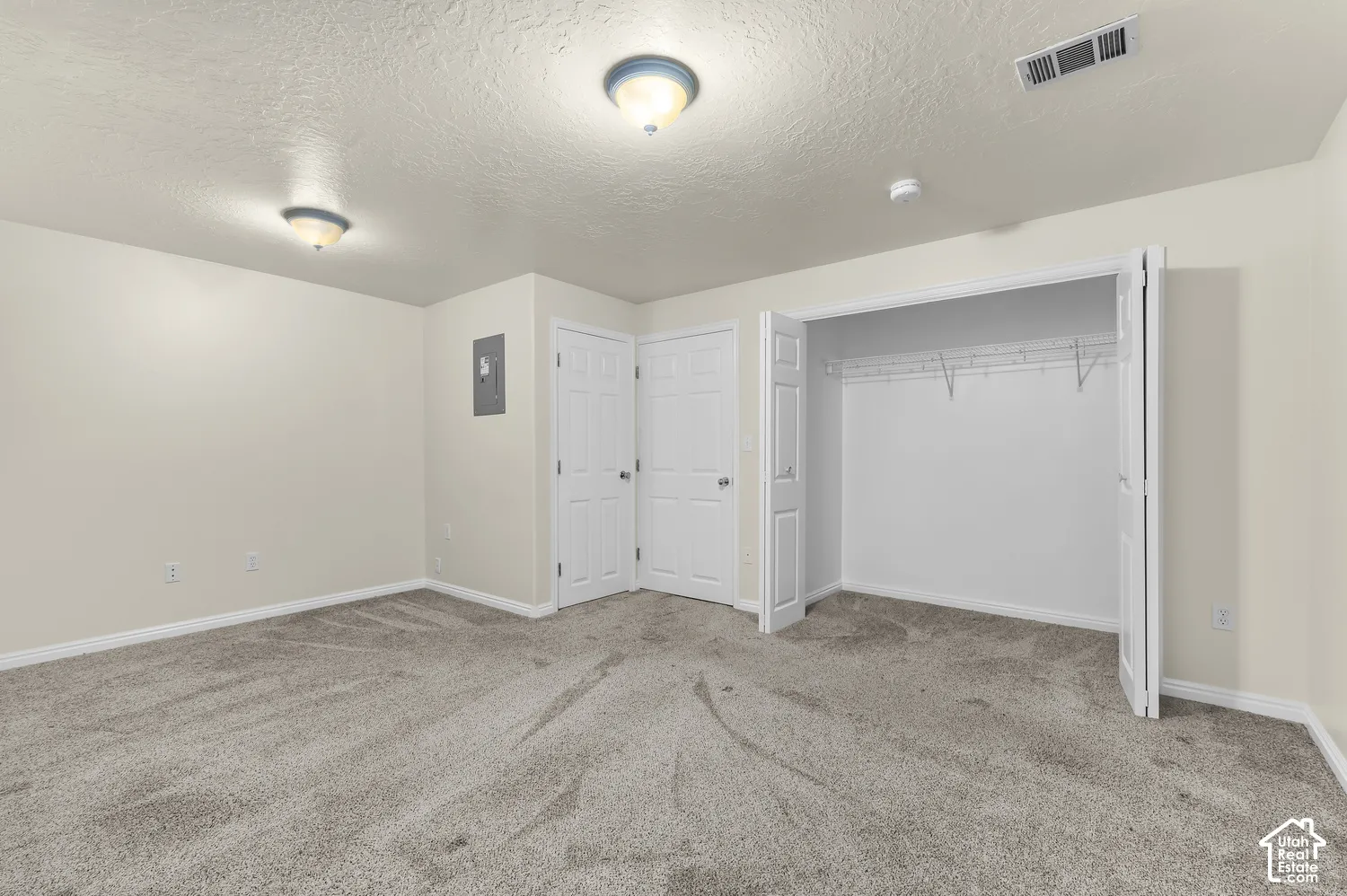 Wall-to-wall carpeting with light-toned walls, bi-fold closet doors, and flush-mount ceiling lighting