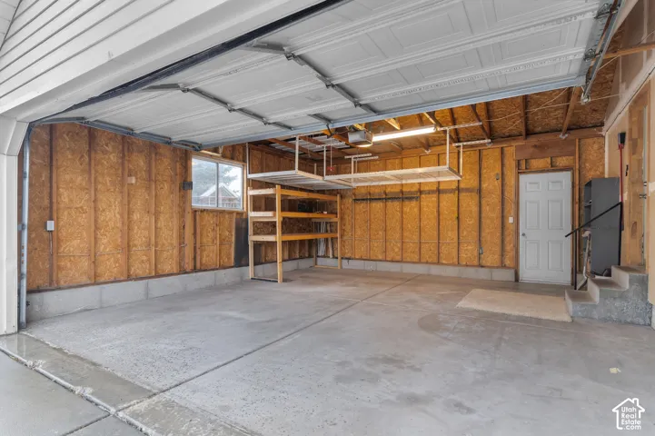 Concrete flooring with overhead storage racks, built-in shelving, and a window