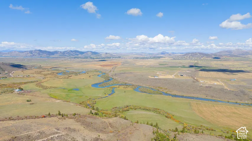 Expansive natural landscape featuring a winding river, distant mountains, and open fields