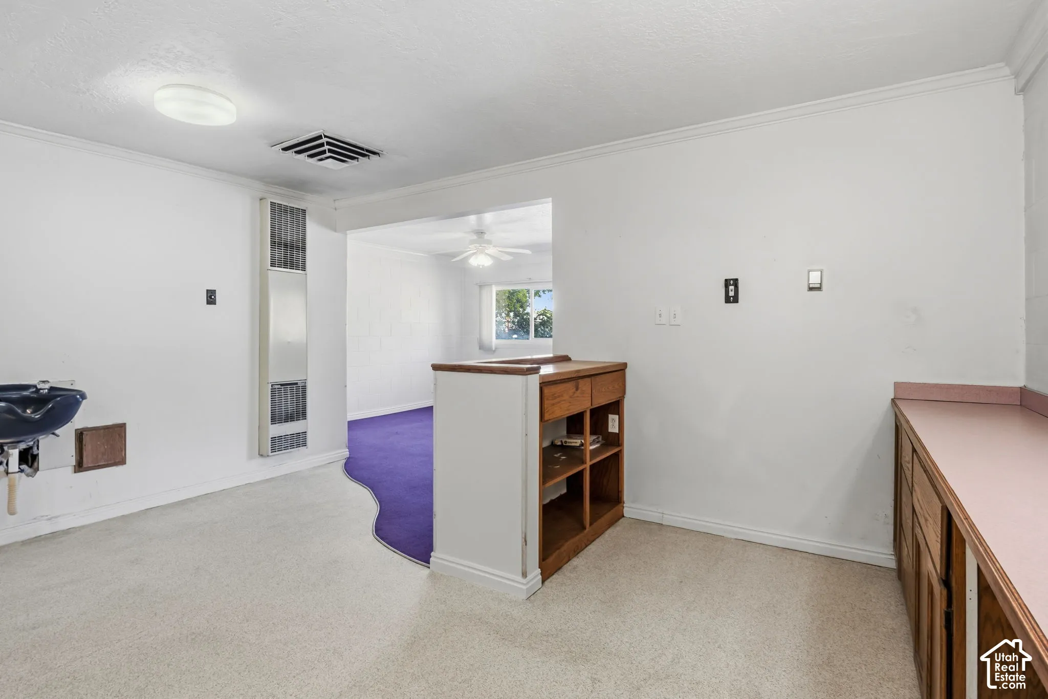 Front desk - Built-in cabinetry with wood-finish doors and pink countertops, recessed shelving, wall-mounted sink, and a wall heater unit, detached building