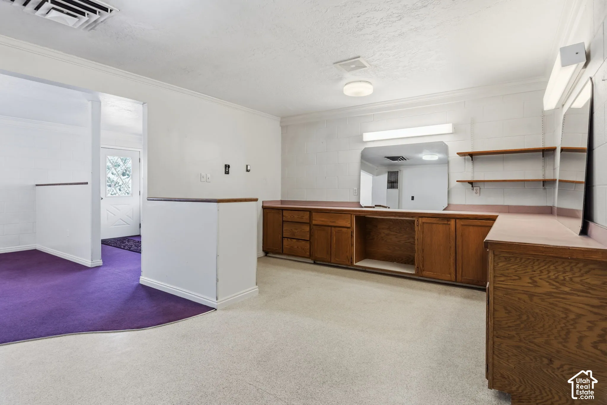 Built-in wooden cabinetry with countertops, wall-mounted mirror with integrated lighting, and ceiling-mounted light fixtures. Was used as a beauty salon