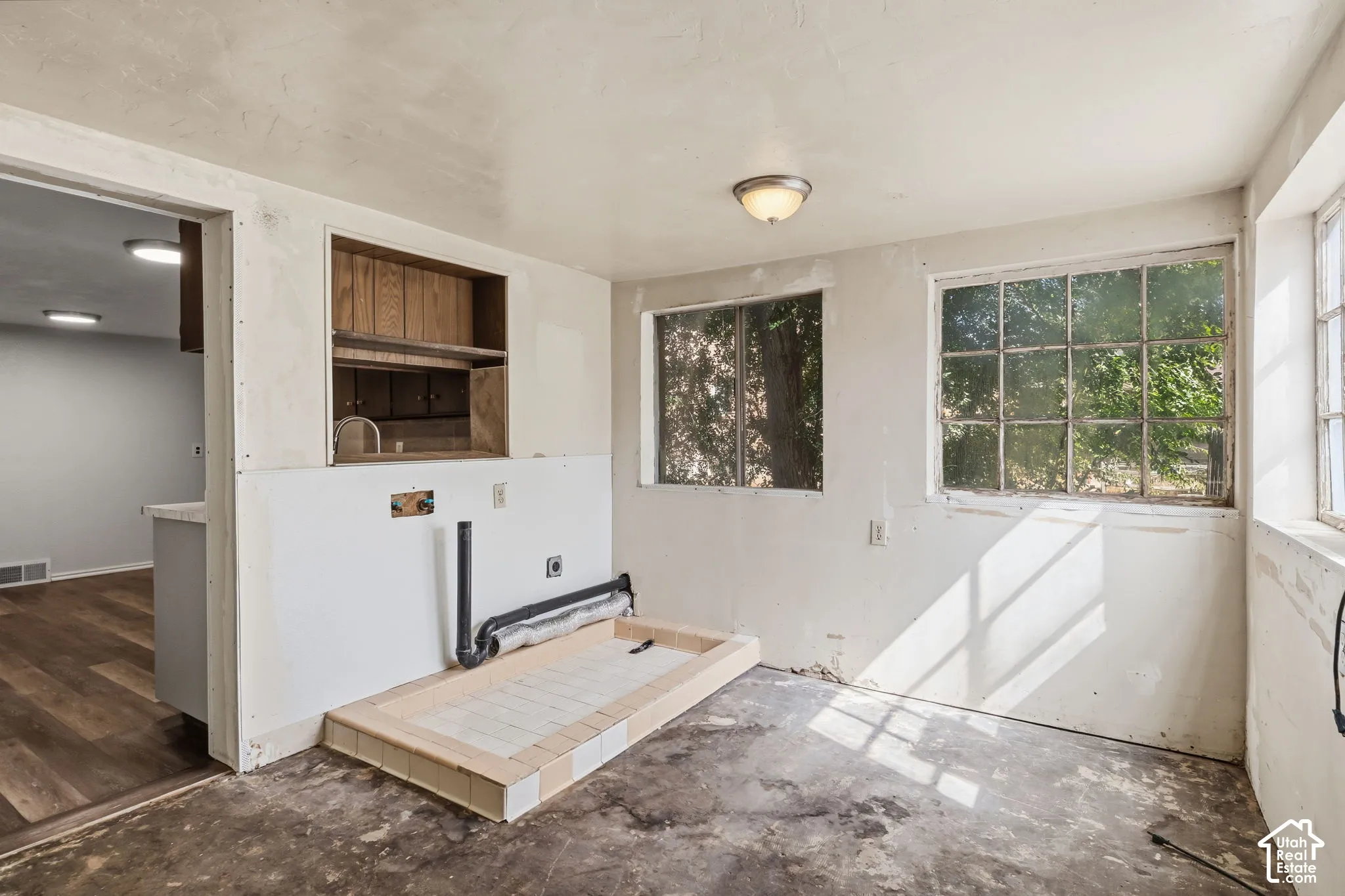 Built-in wood cabinetry, multiple pane windows, and a tiled laundry pan. kitchen pass through for potential formal dining or sunroom