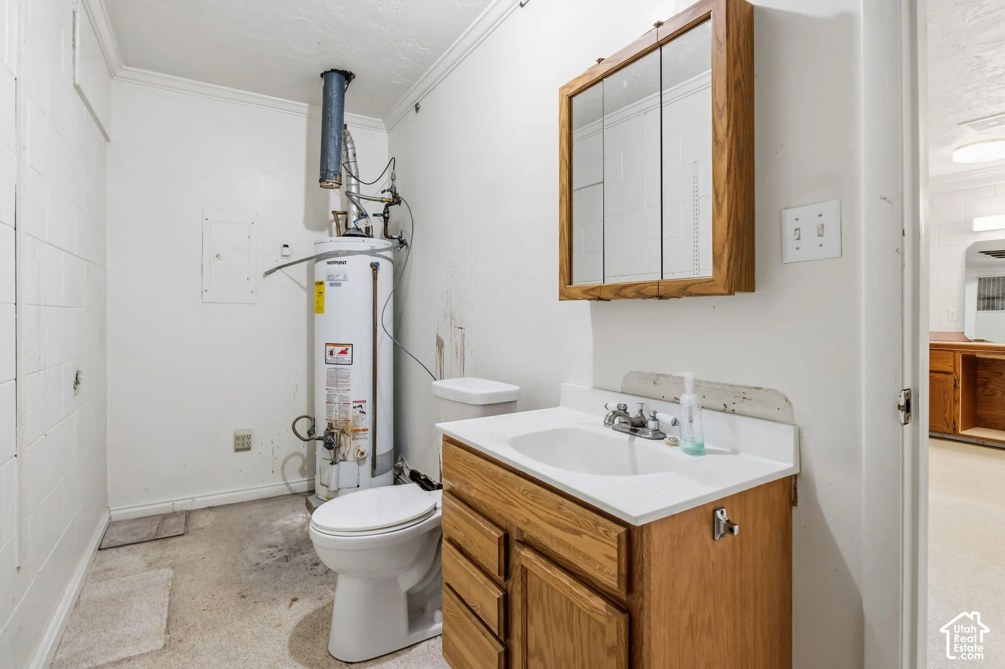 Spacious Half bath.. White vanity with a single basin sink, wood-finish medicine cabinet, and white water heater