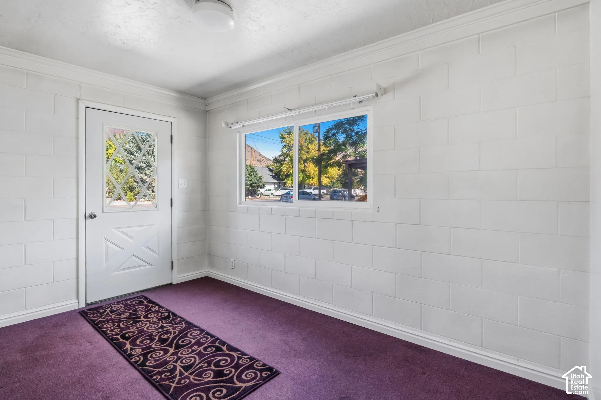 White painted cinder block walls with a single window and a door featuring a decorative glass insert into detached building