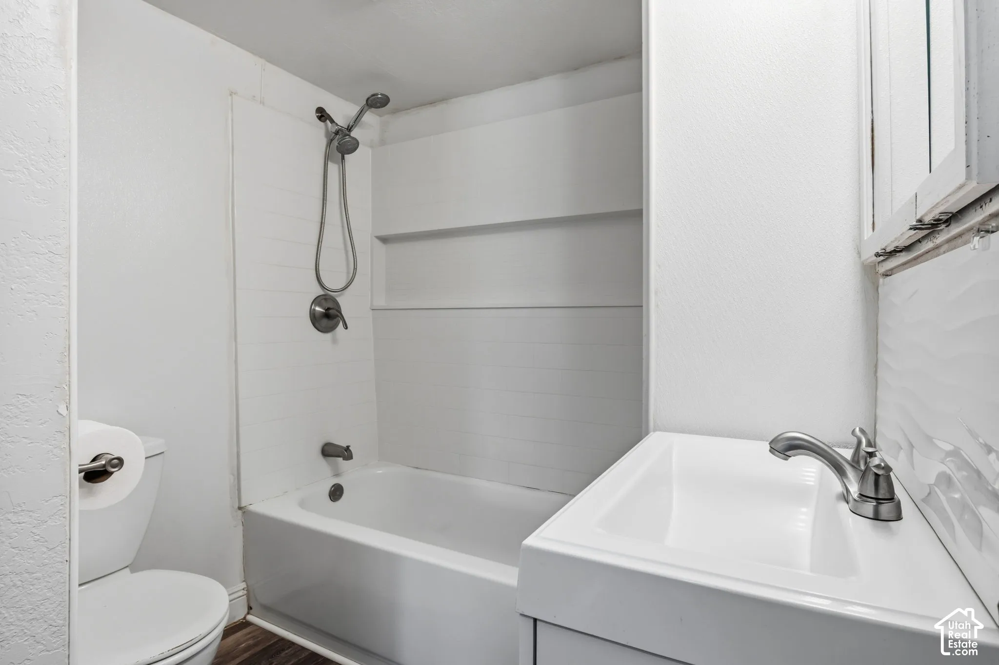 White tub/shower combination with a wall-mounted showerhead and faucet, recently remodeled