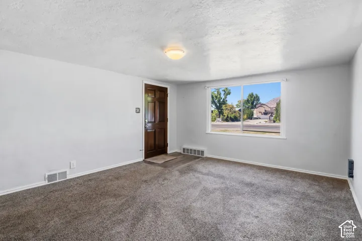 Home - Neutral wall tones with textured ceilings, dark hardwood front door, large window in Home