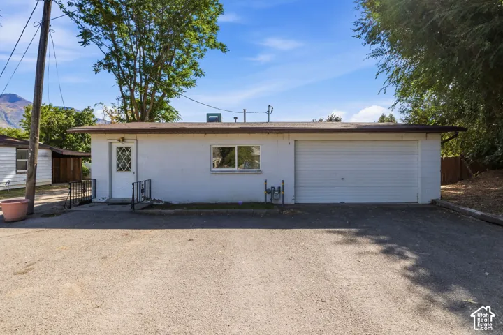 Detached Space with attached two-car garage with a roll-up door, white exterior finish, and a front entry door with a diamond-patterned glass insert