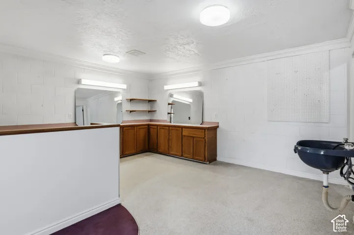 Corner built-in cabinetry with a countertop, two wall-mounted mirrors with integrated lighting, overhead flush-mount lighting, and a utility sink. Detached building