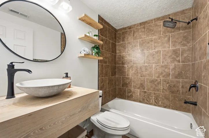 Bathroom featuring a vessel sink, wood-finish vanity, matte black fixtures, a tiled shower surround, and floating shelves