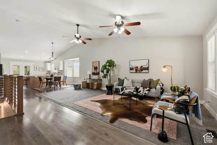 Vaulted ceilings with ceiling fans, wood-finish flooring, kitchen island with seating, pendant lighting, and multiple windows
