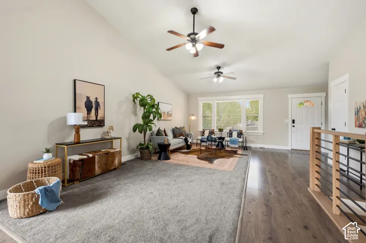 Vaulted ceiling with multiple ceiling fans, wood-finish flooring, and a white paneled entry door