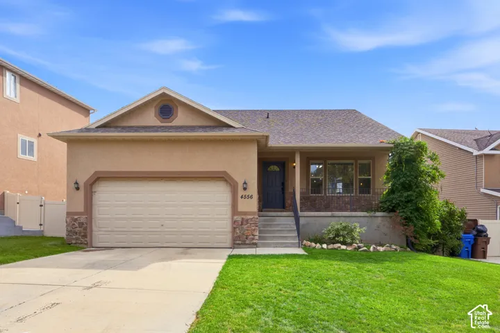 Exterior featuring a two-car garage, stone accents, stucco siding, and a covered entry