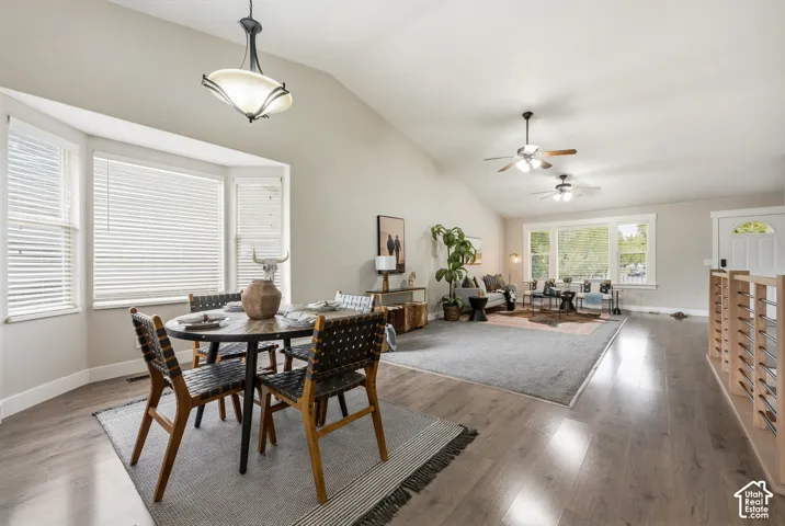 Vaulted ceilings, wood-finish flooring, bay window, multiple ceiling fans, and a white paneled entry door