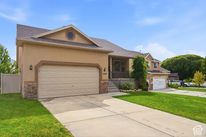 Exterior with stucco finish, stone accents, attached two-car garage, covered porch, and concrete driveway