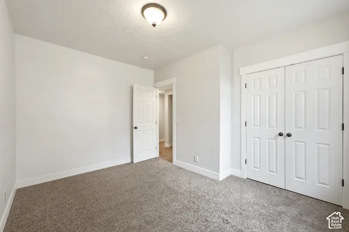 Wall-to-wall carpet flooring, white painted walls, white trim, recessed lighting, and a paneled door