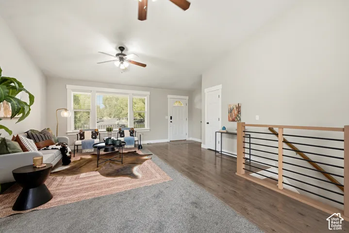 Open-concept living space featuring wood-finish flooring, a contemporary staircase with horizontal railings, a ceiling fan, and multiple windows