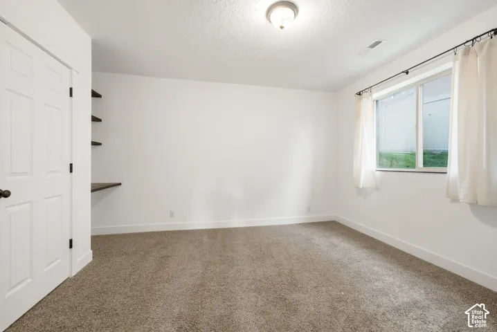 Neutral-toned carpeting, white walls, and a window with natural illumination