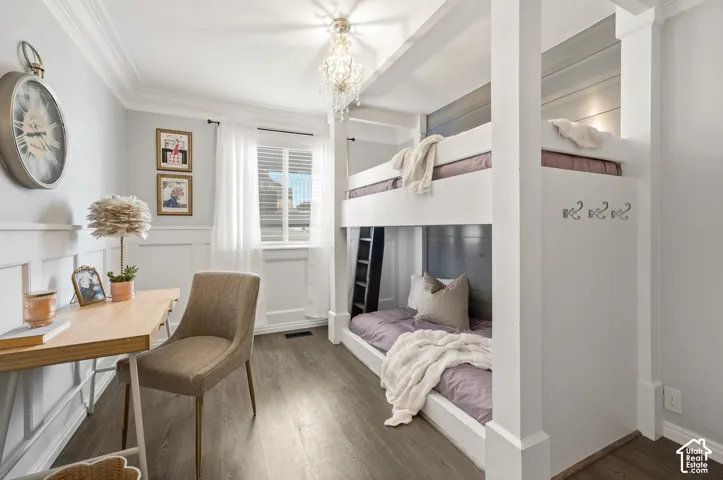 Wood-finish flooring, built-in bunk beds, board and batten wainscoting, crown molding, and a chandelier with decorative accents