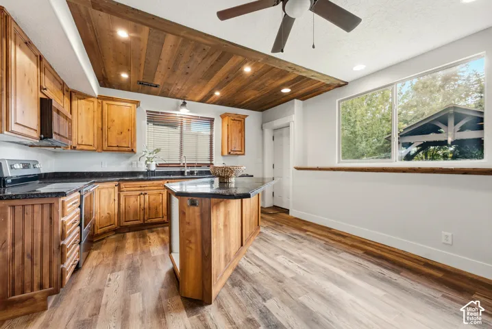 Wood-finish flooring, wood cabinetry, dark countertops, wood plank ceiling with recessed lighting, and a kitchen island with seating