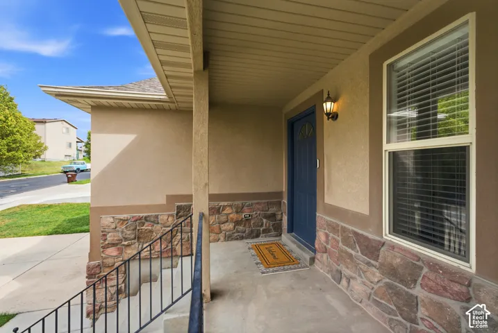 Covered entryway featuring a blue entry door, stone facade, and a wall-mounted light fixture