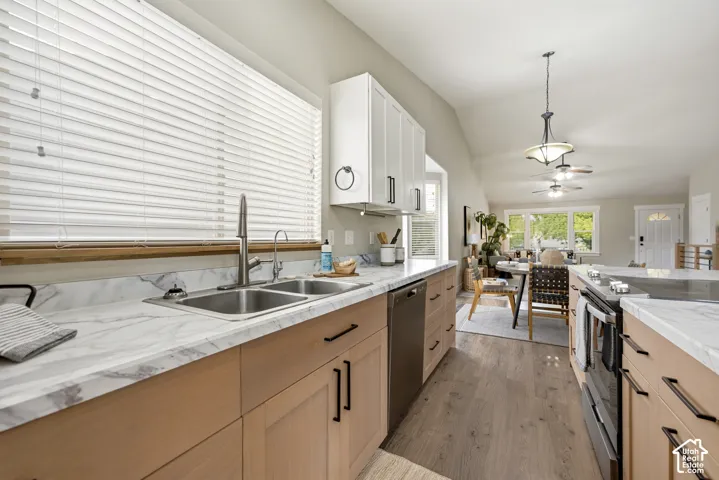 Kitchen featuring light wood-finish lower cabinetry, white upper cabinetry, and a double basin sink