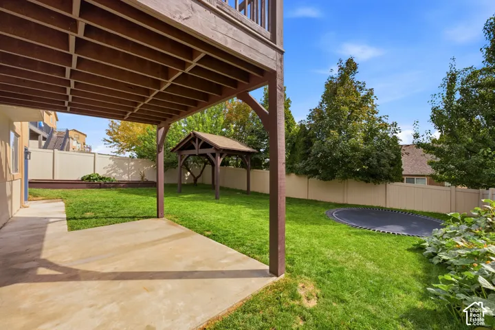 Patio area with overhead deck, expansive lawn, built-in planter boxes, and a wooden gazebo