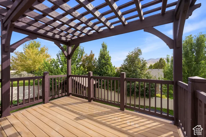 back deck off kitchen featuring wood-finish flooring, a wood pergola, and a dark-stained wood railing