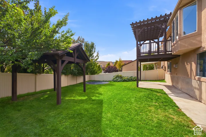 Expansive backyard featuring a lush lawn, privacy fencing, and a covered pergola