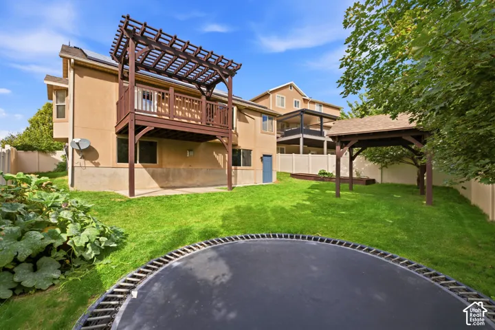 Expansive backyard featuring a manicured lawn, a raised wooden deck with a pergola, a separate wooden gazebo, and a privacy fence