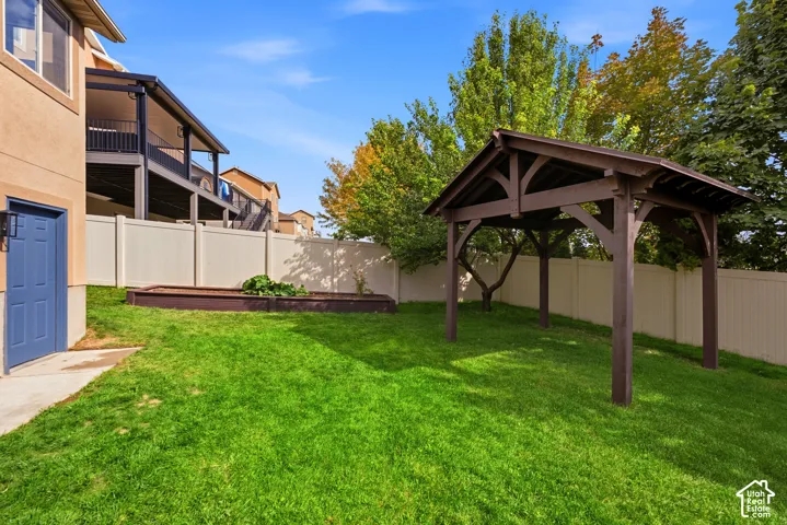 Expansive lawn featuring a built-in wooden gazebo, raised garden bed, and a durable privacy fence
