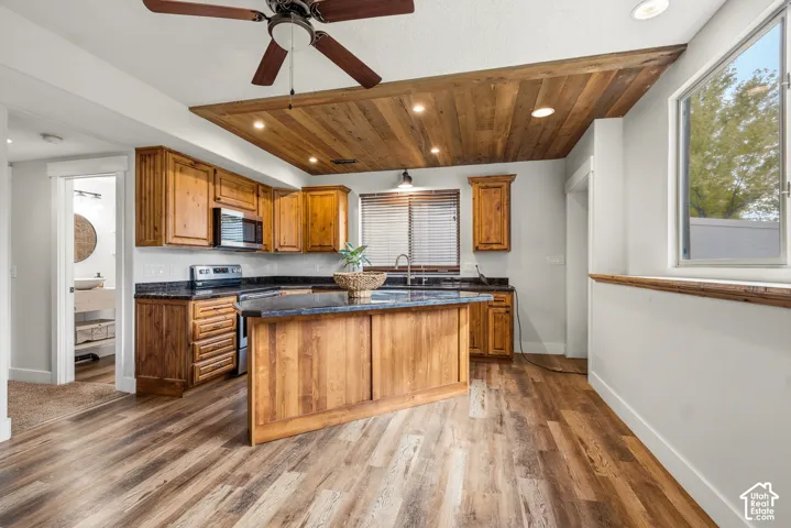 Kitchen featuring wood-finish flooring, wood cabinetry, dark countertops, a central island, and a wood-paneled ceiling with recessed lighting
