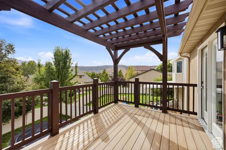 brand new expansive back deck off kitchen with a slatted pergola, composite wood-finish decking, and dark wood railings