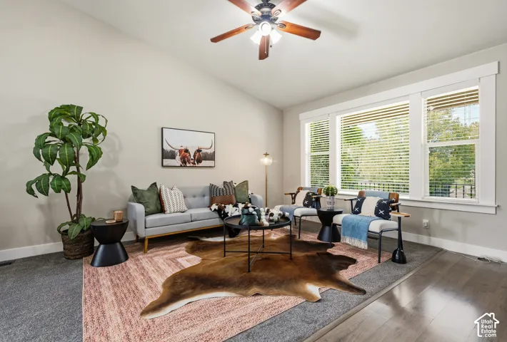 Vaulted ceilings, wood-finish flooring, ceiling fan, and large windows with blinds