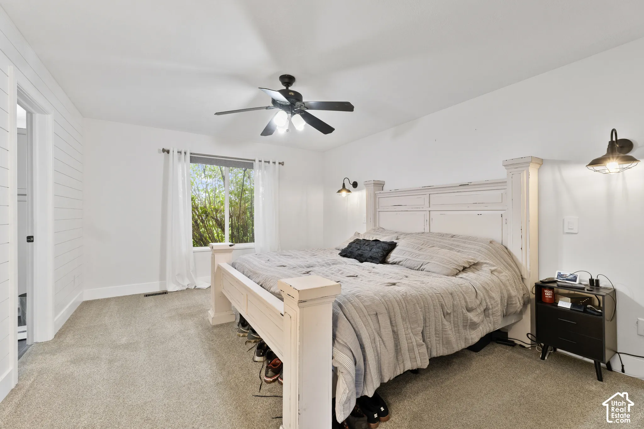 Master Bedroom featuring a ceiling fan with integrated lighting, a window with outdoor scenery, and wall-mounted sconces