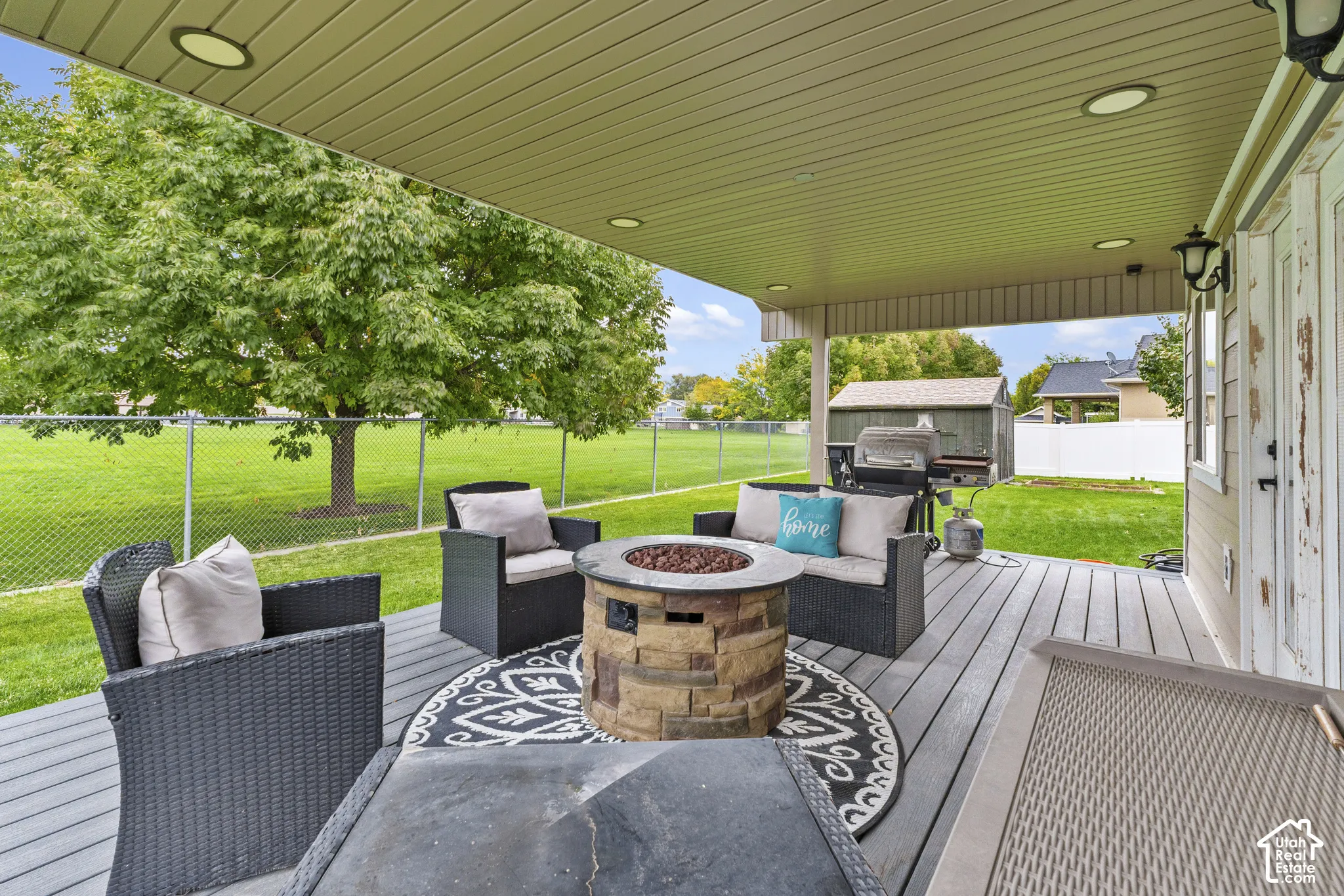 Covered composite deck featuring recessed lighting and a stone-clad fire pit