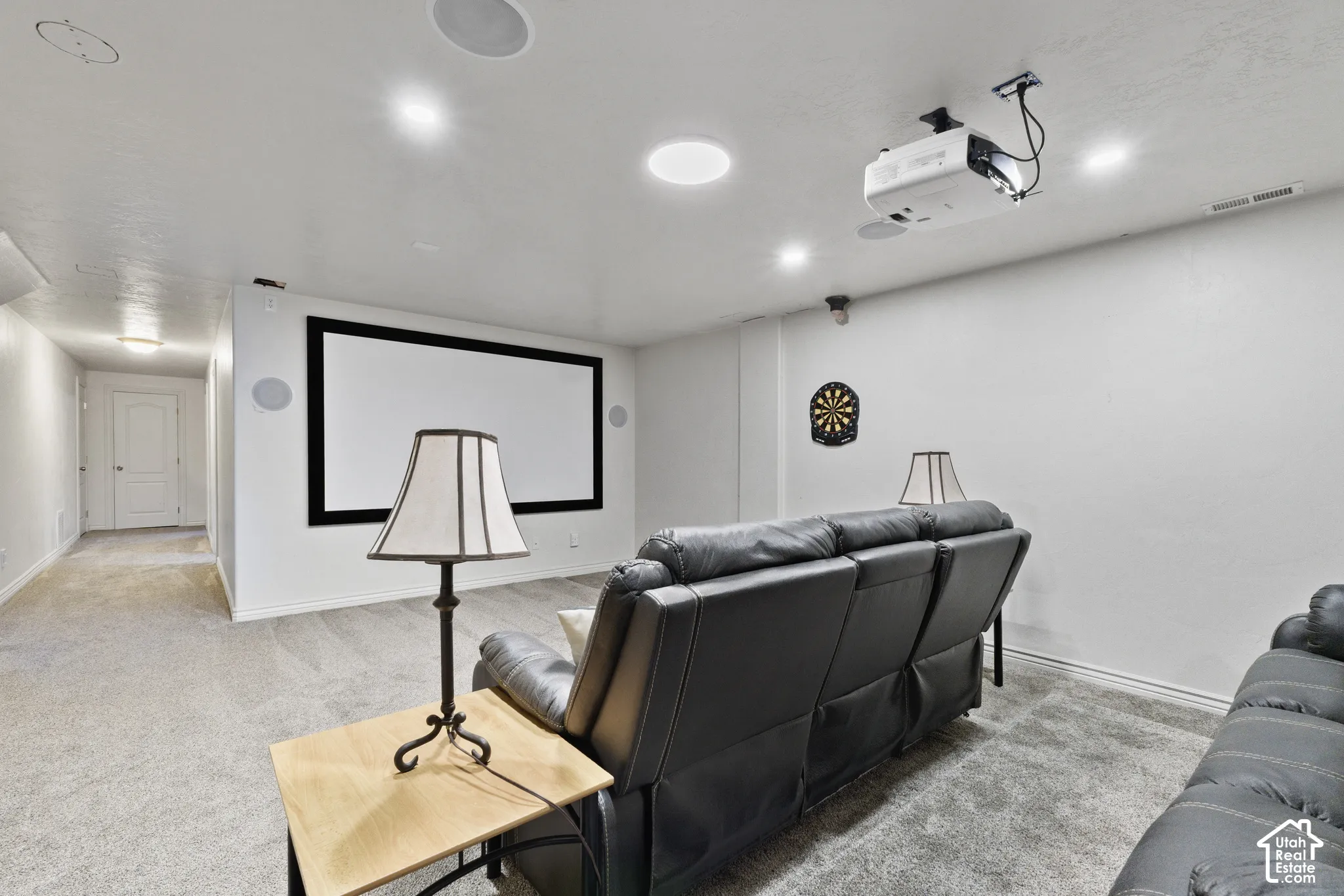Dedicated media room featuring a large projection screen, mounted projector, recessed lighting, and integrated ceiling speakers
