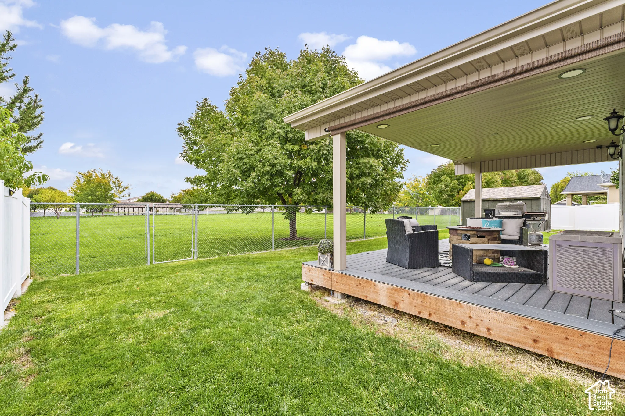 Expansive backyard featuring a covered patio, composite decking, and a chain-link fence