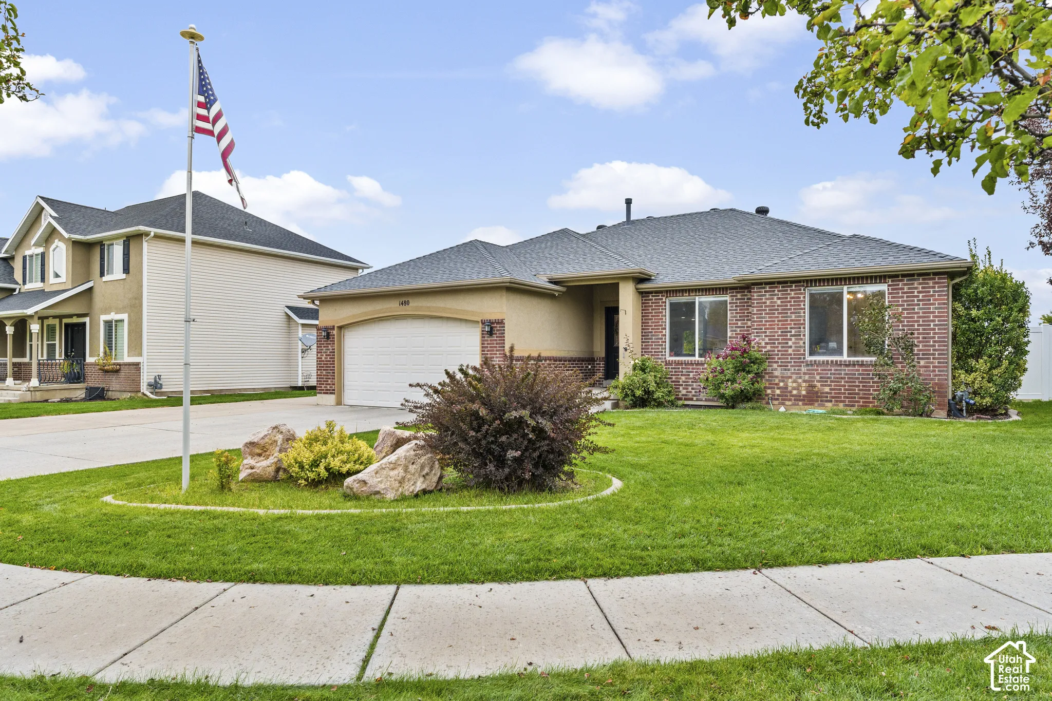 Brick and stucco exterior with a two-car garage, concrete driveway, and front lawn