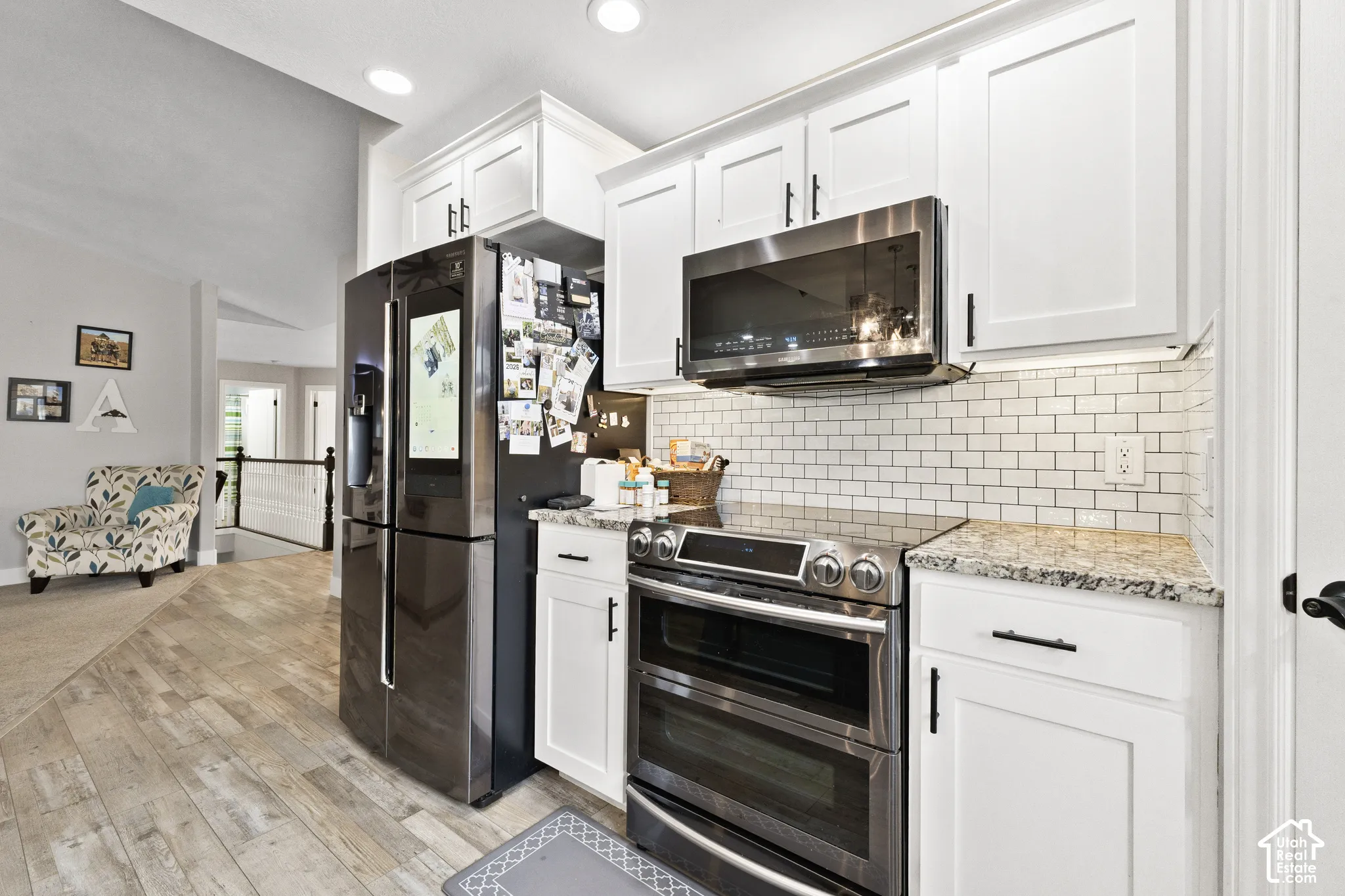 Updated Kitchen featuring white shaker cabinetry, stainless steel appliances, granite countertops, and subway tile backsplash